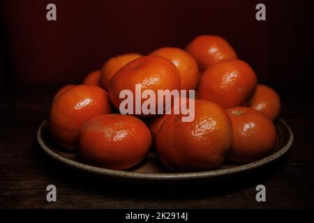 Orange mandarine sur une assiette dos foncé Banque D'Images