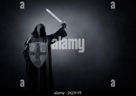 Chevalier foncé avec épée et bouclier dans l'obscurité de la nuit Banque D'Images