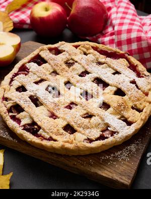 tarte aux pommes traditionnelle cuite autour d'un panneau de bois brun et de pommes rouges fraîches, vue du dessus Banque D'Images