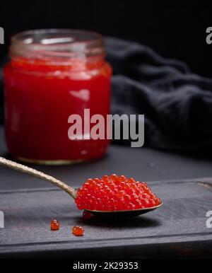 caviar rouge granuleux frais dans un pot en verre sur une table en bois Banque D'Images