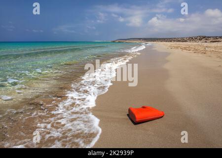 D'huile en plastique rouge vif (ou liquide vaisselle) récipient sur belle plage préservée. L'abandon de détritus plastiques mer concept. Karpazz, Chypre du Nord. Banque D'Images