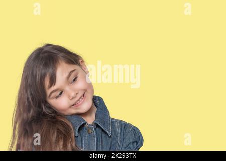 Une petite fille bronzée souriante pose sur fond jaune. Banque D'Images