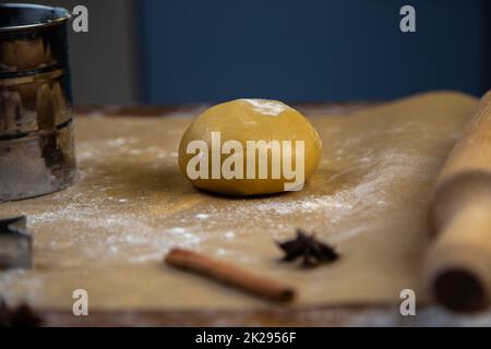 Il y a une pâte sur le parchemin, un peu arrosé de farine, une rollpin, des emporte-pièces, de la cannelle et un pot de farine en métal sont visibles autour. Banque D'Images