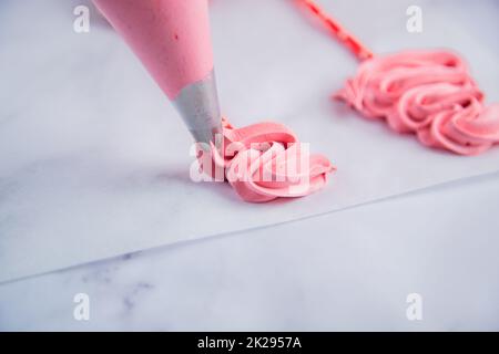 Dans le sac à pâtisserie, un bizet rose est posé sur du papier à pâtisserie avec des boucles sous la forme d'un arbre de Noël. Banque D'Images