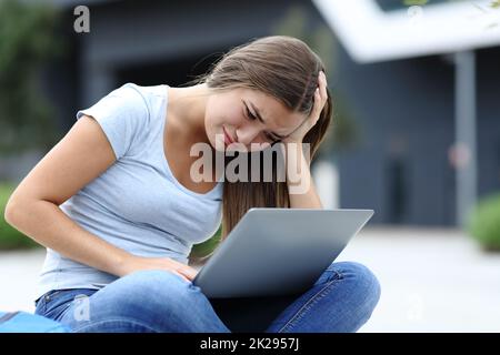 Une jeune femme triste qui a vérifié son ordinateur portable dans la rue Banque D'Images