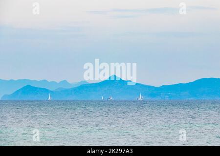 Bateaux à voile et montagnes Plage de Vouliagmeni près de Voula Grèce. Banque D'Images