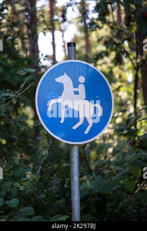 Un panneau bleu et blanc avec un cheval d'équitation marque un sentier équestre supplémentaire. Banque D'Images