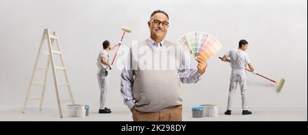 Homme mature tenant une palette de couleurs et peintre travaillant dans le dos Banque D'Images