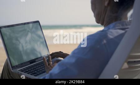 Femme sénior se détendre sur des chaises en profitant du temps sur la plage de vacances de travail avec ordinateur portable Banque D'Images