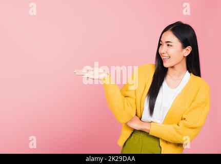 une femme sourit debout et présente le produit en tenant quelque chose sur le côté de la paume Banque D'Images