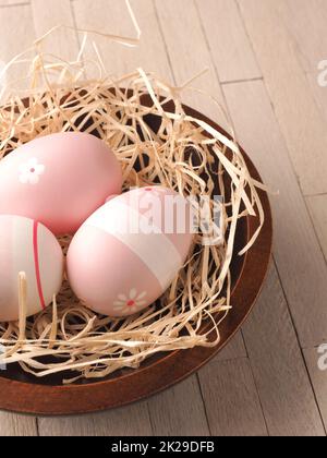 Trois œufs de Pâques roses dans un nid Banque D'Images