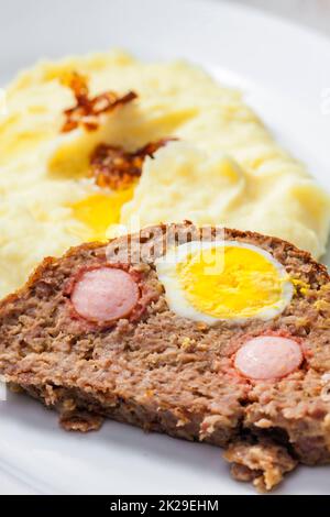 pain de viande rempli d'œufs et de saucisses servi avec une purée pommes de terre et oignons frits Banque D'Images