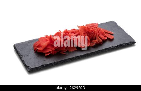 gingembre rose mariné sur un tableau en pierre noire, épice pour sushi. Arrière-plan blanc Banque D'Images