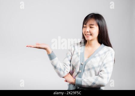 Souriante bonne femme présentant un produit tenant quelque chose sur le côté de la paume Banque D'Images