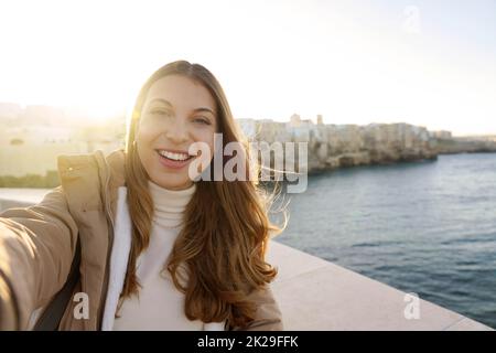 Charmante femme faisant selfie photo à Polignano une ville de jument au coucher du soleil, Apulia, Italie Banque D'Images