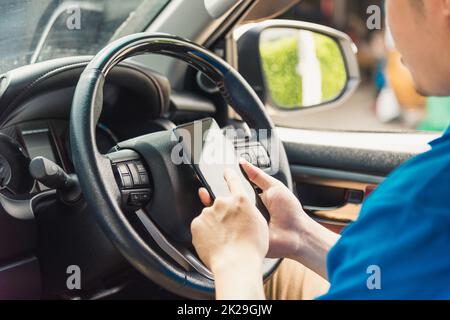 livreur en ligne tenant les livraisons à l'intérieur de la voiture et en utilisant le téléphone intelligent mobile pour vérifier l'emplacement Banque D'Images