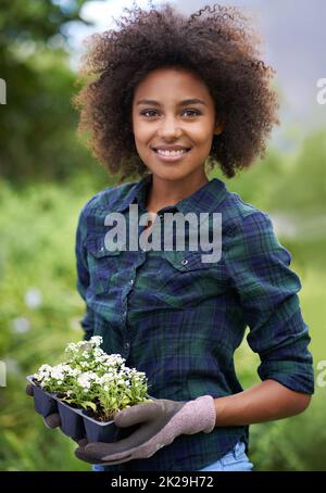 Fier parent de plante. Portrait d'une jeune femme heureuse tenant un plateau de semis dans un jardin. Banque D'Images