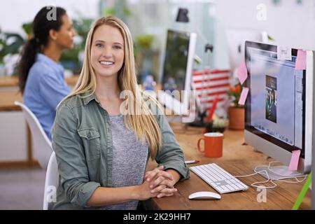 Le design est sa passion. Portrait d'une jeune designer féminine attrayante assise à son bureau. Banque D'Images