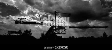 Pelle hydraulique à roue à godet géante sur des faisceaux de soleil de jour nuageux Banque D'Images