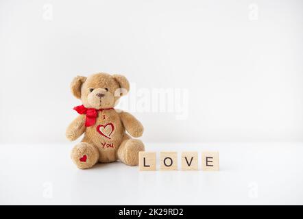 Adorable ours en peluche avec un cœur isolé sur un fond blanc. Lettrage amour, concept de vacances de la Saint-Valentin. Banque D'Images