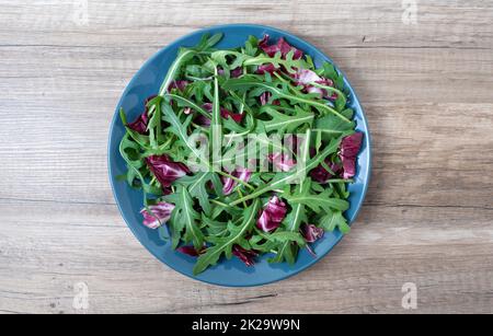 Salade de feuilles mélanger le vert, le jus de collation, dans une assiette sur une table en bois Banque D'Images