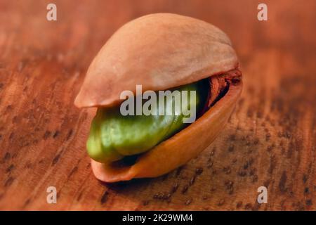 Profondeur de champ (extreme close up) seule la pistache en coque de noix verte, visible, sur planche de bois. Banque D'Images