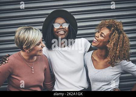 Les meilleurs amis sont faits pour rire. Photo d'un groupe diversifié d'amis féminins s'embrassant les uns les autres à l'extérieur. Banque D'Images