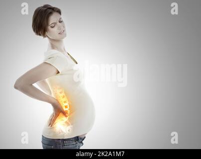 Faire face à l'inconfort de la grossesse. Vue rognée d'une femme enceinte qui la tient dans le bas du dos en douleur. Banque D'Images