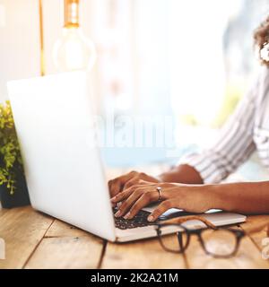 Theres un monde plein de possibilités dehors là. Photo courte d'une jeune femme méconnue utilisant son ordinateur portable sur une table en bois. Banque D'Images