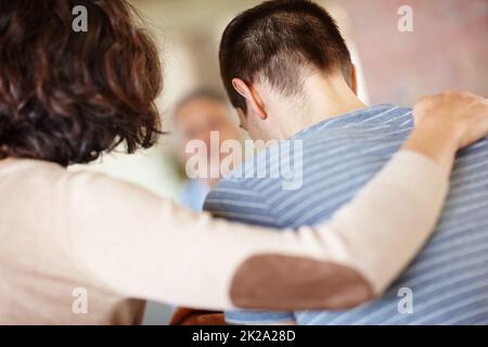 Étaient tous ici pour vous. Vue arrière d'une mère attentionnée qui console son fils adulte. Banque D'Images