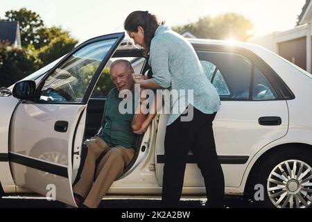 Je vous apporte le soutien dont vous avez besoin. Photo d'une femme aidant son père senior à sortir de la voiture. Banque D'Images