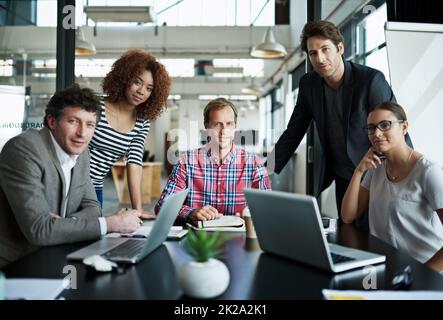 Les grands esprits de la conception. Portrait d'un groupe de travailleurs de bureau souriants assis autour d'une table. Banque D'Images