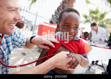 Chaque enfant mérite un départ sain dans la vie. Photo d'un médecin bénévole qui donne des examens à des enfants défavorisés. Banque D'Images