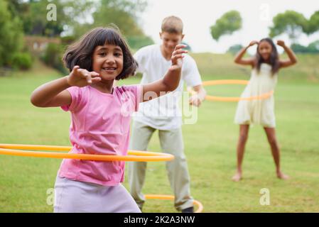 Faites tourner comme vous n'avez jamais tourné auparavant. Trois enfants jouant avec des hula Hoops à l'extérieur. Banque D'Images