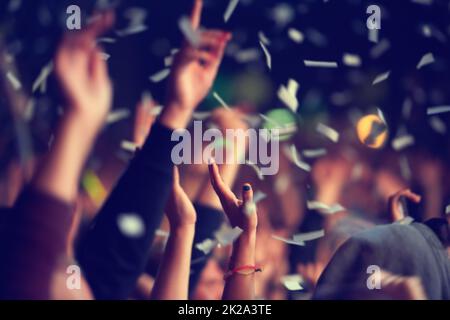 Sauvage et gratuit. Un public de festival de musique jetant des confetti dans l'air dans la célébration. Banque D'Images