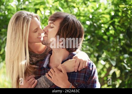 Jeune et plein de passion. Portrait d'un jeune couple souriant qui s'embrasse dans le parc. Banque D'Images