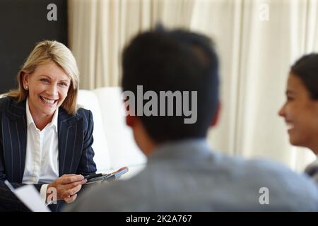 S'assurer que tout s'ajoute. Photo d'une femme souriante à l'aide d'une calculatrice lors d'une réunion assise. Banque D'Images