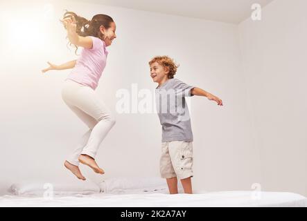 Quelle hauteur pouvez-vous atteindre ? Photo de deux petits enfants sautant sur un lit. Banque D'Images