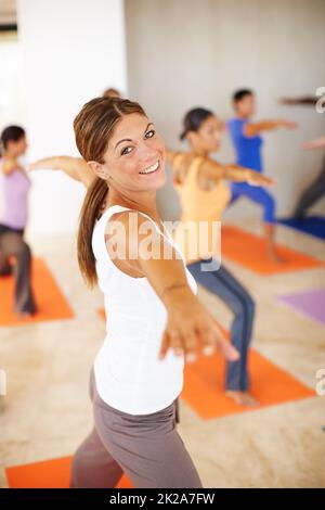 S'étirant. Une magnifique jeune femme dans un cours de yoga dans un poste de yoga. Banque D'Images