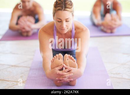 S'étirer pour le bien-être. Jeune instructeur de yoga menant une classe. Banque D'Images