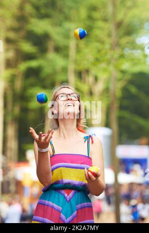 Ses compétences en jonglage sont sur le ballon. Photo d'une jeune femme attirante qui jongle à un festival en plein air. Banque D'Images