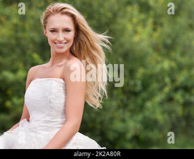 Magnifique le grand jour. Une jeune mariée magnifique souriant et regardant étourdissante dans sa robe de mariage aux côtés de l'espace d'imitation. Banque D'Images