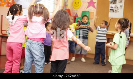 Danse pour se débarrasser de toute l'énergie. Les élèves d'âge préscolaire sautant et dansant autour de s'amuser. Banque D'Images