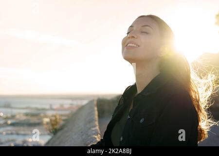 Profil de contre-jour d'une femme qui respire de l'air frais profond au lever du soleil Banque D'Images