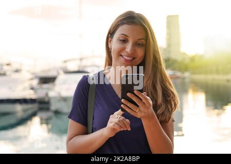 Tourist girl défilant sur l'écran tactile de smartphone à la recherche de l'hôtel. Voyageur femme dactylographiant sur un téléphone mobile réservant une chambre pour la nuit. Concept de voyages de dernière minute. Banque D'Images