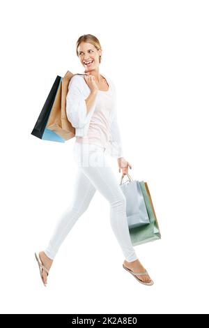 Shopping frénésie juste pour moi. Portrait studio d'une jeune femme heureuse portant des sacs à provisions et sautant sur fond blanc. Banque D'Images