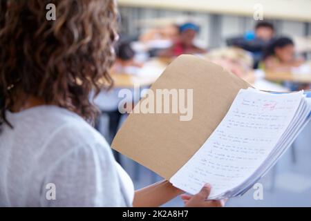 Prêt à annoncer les marques. Vue sur l'épaule d'un enseignant lisant les notes des élèves. Banque D'Images