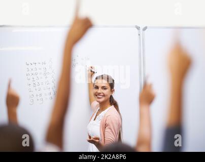 Qui connaît la réponse. Un groupe d'étudiants levant les mains en classe. Banque D'Images