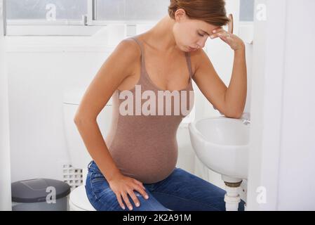 Des vagues de nausées. Une femme enceinte aux prises avec la maladie du matin dans la salle de bains. Banque D'Images