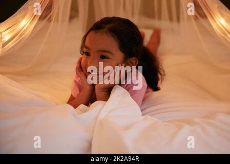 J'ADORE les lueurs. Photo d'une petite fille mignonne couché sur son ventre sur un lit. Banque D'Images